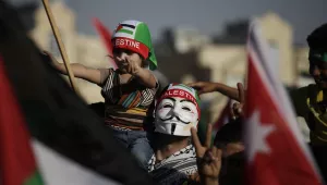 A man wears a Guy Fawkes mask and carries his daughter during a celebration by the Muslim Brotherhood movement to declare victory of Gaza and Hamas against Israel, in Amman, Jordan, Friday, Aug. 29, 2014. (AP Photo/Mohammad Hannon)