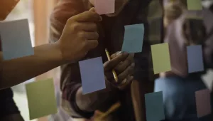 Office workers using sticky notes on a wall