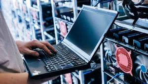 A technician holding a laptop working in a server room
