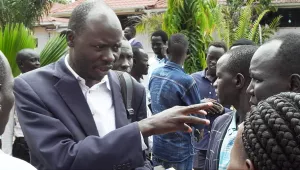 Peter Ajak speaking to a small group outside.