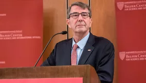 Ash Carter standing at a podium in front of crimson Belfer Center backdrops.