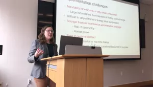 Conleigh Byers speaks at a podium in front of a projector screen.