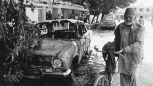 An old man walks past a gutted car in downtown Kabul, Thursday, June 25, 1992. 