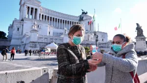 Women wearing face mask disinfect their hands in central Piazza Venezia, Rome