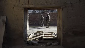 Security personnel are framed in a damaged door