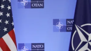 U.S and NATO flags in front of a NATO conference backdrop.