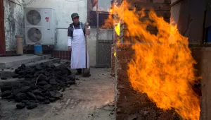 A worker waits to shovel coal to feed kitchen stoves at the Liuminying village in Beijing, China