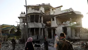 Afghan security personnel inspect a damaged building