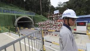 A worker stands near a tunnel