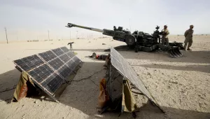 Marines stand near an artillery piece that links to solar panels during an exhibition of green energy technology in Twentynine Palms, Calif. 