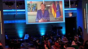 German Chancellor Angela Merkel, on a screen, speaks via videoconference