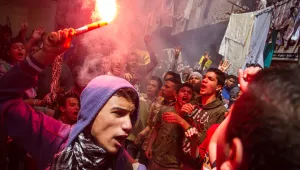 An Egyptian youth carries a lit flare 