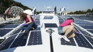 Crew members of the Energy Observer, a former race boat turned into a autonomous navigation with hydrogen, clean the solar panels of the boat in Paris