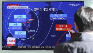 A man watches a TV screen showing a local news program reporting about North Korea's missile launch