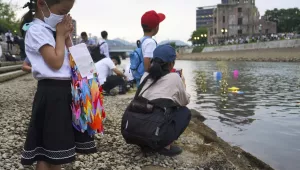 Saki Morioki, 5 years old, prays as paper lanterns float along the Motoyasu River in front of the Atomic Bomb Dome, Thursday, Aug. 6, 2020. in Hiroshima, western Japan. Japan marked the 75th anniversary Thursday of the atomic bombing of Hiroshima. The official lantern event was cancelled to the public due to coronavirus but a small group of local representatives released some lanterns. (AP Photo/Eugene Hoshiko)