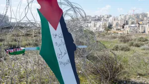 Protesters posted a placard with the colors of the Palestinian flags and Arabic that reads "Jerusalem is the eternal capital of Palestine," at a barbed wire fence surrounding the Israeli separation wall and the Israeli settlement of Mod'in Ilit, during a protest against Israel and the Untied States in the West Bank village of Bil'in, near Ramallah, Friday, Jan. 31, 2020.