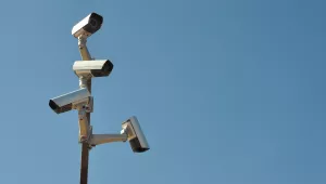 surveillance cameras on post against blue sky