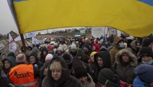 A Ukrainian volunteer holds a the country's flag and directs hundreds of refugees
