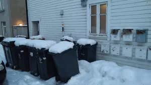 Waste bins on a snowy sidewalk in Tromso, Norway.