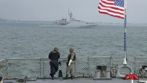 Members of the U.S. Navy of the Arleigh Burke-class guided-missile destroyer USS Ross look on Britain's Royal Navy patrol ship 