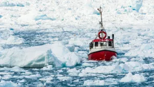A fishing boat navigates through sea ice in Greenland.