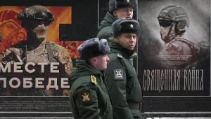 A military patrol passes by a street exhibition of military posters named 'Together to Victory' dedicated to Russian army in St. Petersburg, Russia, Monday, Feb. 24, 2025.