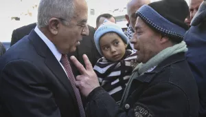 Palestinian Prime Minister Salam Fayyad, left, talks to a man during a visit to the West Bank city of Nablus. Saturday, Feb. 4 , 2012.
