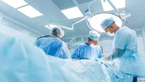 Surgeons in binocular lenses operate the patient lying under anesthesia in the operating room