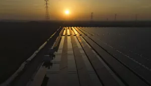 The sun sets over electric pylons along a solar farm 