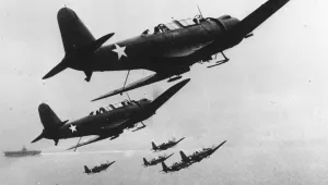 Six U.S. Navy scout planes in flight above their carrier