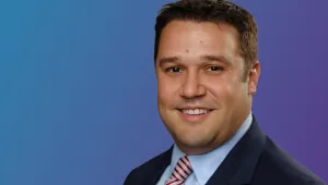 Jeremy Harrell, a middle-aged white man in a suit, against a blue background.