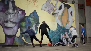 A youth worker and children at a youth center play soccer in front of a mural which includes a Puffin bird in Torshavn, Faroe Islands, Wednesday, March 18, 2015.