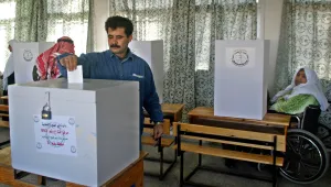 Salima Abu Salim, 59, right, in her wheelchair, looks on as her son Ahmed casts his ballot at a polling station in the central Gaza Strip town of Deir el-Balah, Thursday Jan. 27, 2005. Palestinians voted in 10 Gaza towns Thursday, the first ever municipal elections in the coastal strip and a key electoral test for the Islamic militant group Hamas which is shifting its focus toward politics after agreeing to suspend attacks on Israel.