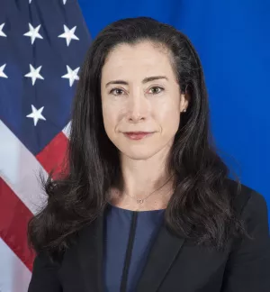 Headshot of Mallory Stewart with an American flag over a blue background