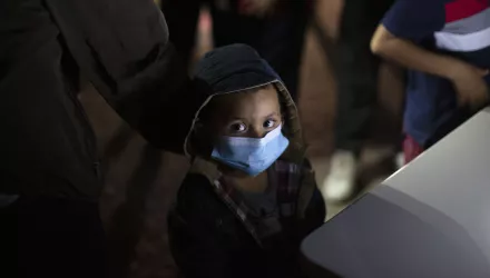 An unaccompanied minor looks up as he waits to answer questions from a U.S. Border Patrol agent at an intake site after he was smuggled on an inflatable raft across the Rio Grande river in Roma, Texas, Wednesday, March 24, 2021. 
