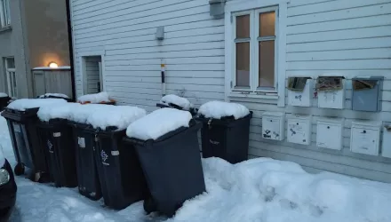 Waste bins on a snowy sidewalk in Tromso, Norway.