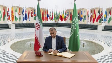 Hossein Amirabdollahian signs a register at the Saudi Foreign Ministry flanked by flags of Saudi Arabia and Iran.