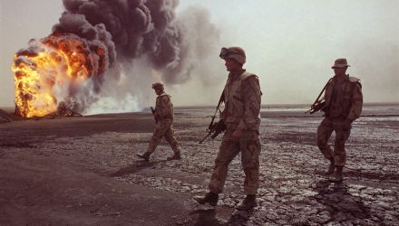 In this March 7, 1991 file photo, a U.S. Marine patrol walks across the charred oil landscape near a burning well during perimeter security patrol near Kuwait City.