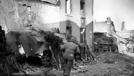 An American soldier runs past a burning German half-track in the recaptured town of La Gleize, Belgium, in 1944 during the Battle of the Bulge in World War II.