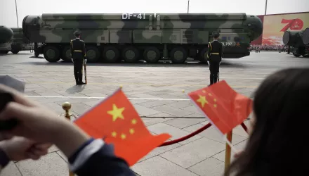 Spectators wave Chinese flags as military vehicles carrying DF-41 nuclear ballistic missiles roll during a parade to commemorate the 70th anniversary of the founding of Communist China in Beijing on Oct. 1, 2019.