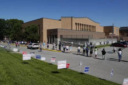 Voters wait in a line outside Broad Ripple High School to vote in the Indiana primary in Indianapolis, Tuesday, June 2, 2020 after coronavirus concerns prompted officials to delay the primary from its original May 5 date.