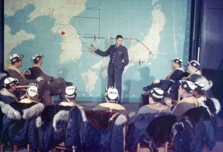 Maj. Harry Bailey points out the often-visited target of Sinuiju, North Korea. On the right of the map is a red dot that represents their starting point, Yokota Air Base near Tokyo, Japan.