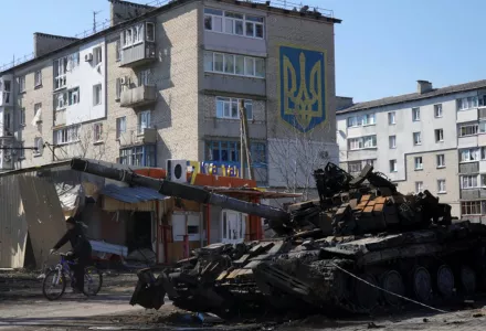 Image of tank in Kiev in front of a building marked with Ukraine's national coat of arms. 