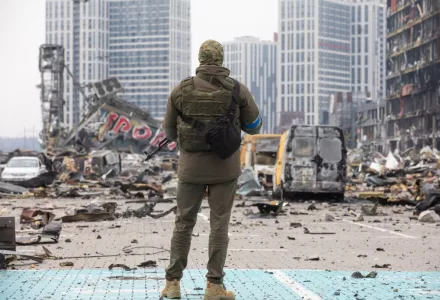 Soldier standing before rubble in Ukraine