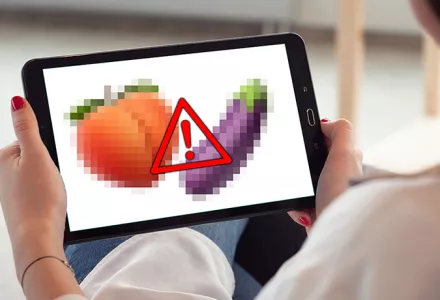 A woman views a peach and eggplant emoji on her tablet