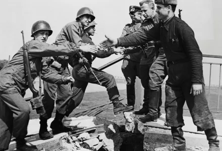 US troops of the 69th Infantry Division (left), shake hands with Russian troops in a staged photo on the wrecked bridge over the Elbe at Torgau, Germany, to mark the previous day's link-up between American and Soviet forces, 26th April 1945. Among the Americans are Bernard E. Kirschenbaum and Richard Johnson (second and third from left, respectively).