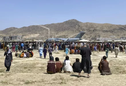 Hundreds of people gather near a U.S. Air Force C-17 transport plane at the perimeter of the international airport in Kabul, Afghanistan, Aug. 16, 2021. More than a year after the Taliban takeover that saw thousands of Afghans rushing to Kabul's international airport amid the chaotic U.S. withdrawal, Afghans at risk who failed to get on evacuation flights say they are still struggling to find safe and legal ways out of the country. 