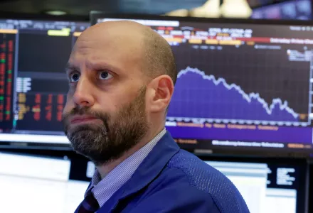A man working on the floor of the New York Stock Exchange reacts to a steep plunge in the stock market. 