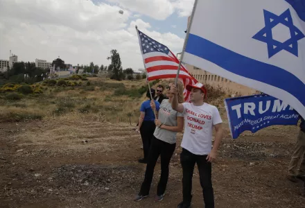 Israelis hold American and Israeli flags with the new U.S. embassy in the background in Jerusalem, Monday, May 14, 2018.
