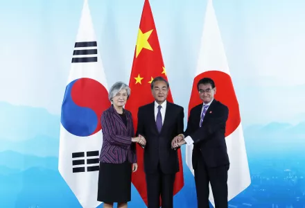 Chinese Foreign Minister Wang Yi, center, holds hands of his South Korean counterpart Kang Kyung-wha, left, and Japanese counterpart Taro Kono for photos ahead of their meeting in Beijing on Aug. 21, 2019.